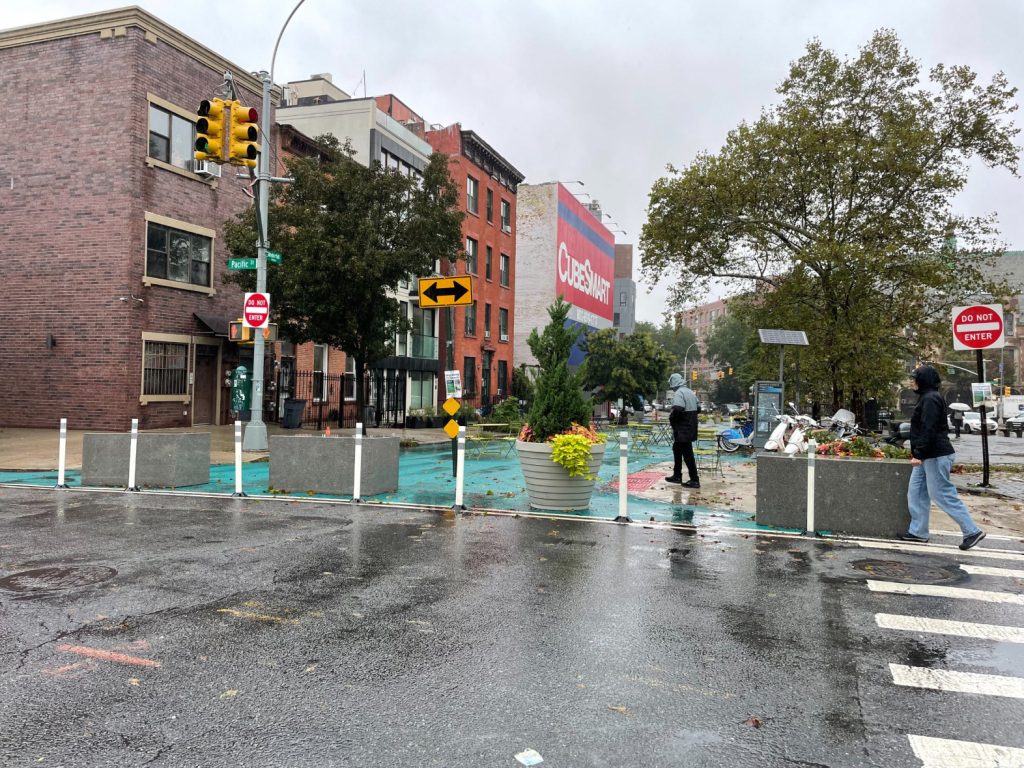 An overview image of the block closed off at the intersection of Pacific, Washington and Underhill. There are large boulders, planters, and bollards blocking off the street.